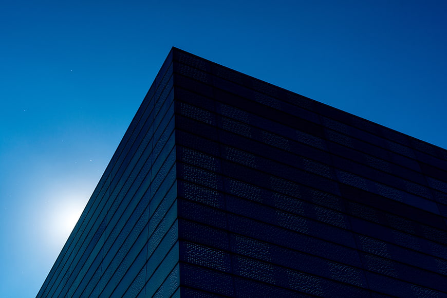 Modern Blue Glass Building Corner Against Clear Sky