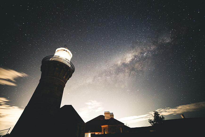 Lighthouse Silhouette Under Milky Way Night Sky
