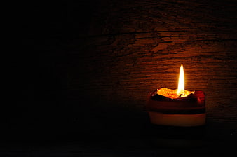 Lit Candle Flame Against Dark Textured Wooden Background