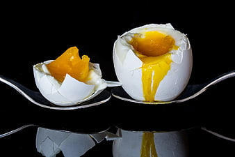 Soft-boiled egg with runny yolk on silver spoon