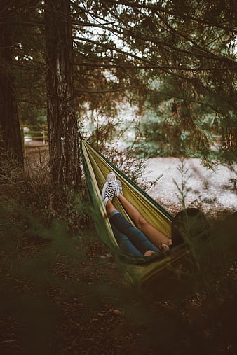 Woman relaxing in green hammock in forest