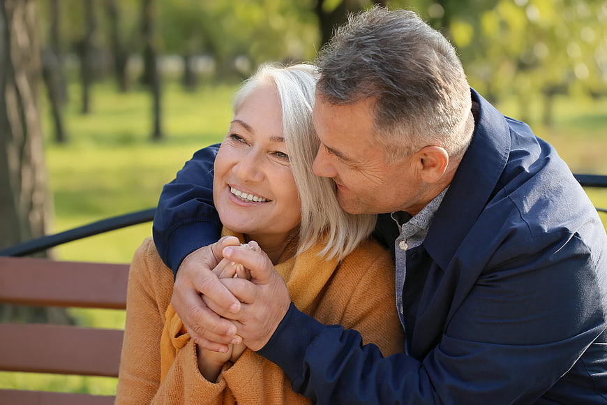 Happy Senior Couple Embracing on Park Bench