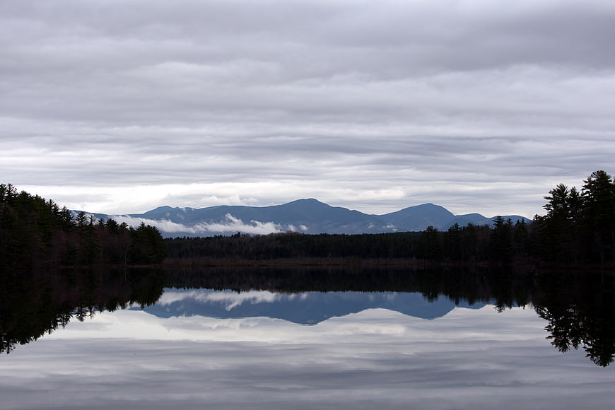 Serene Lake Reflection of Mountains Under Cloudy Sky