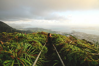 Woman hiking lush mountain ridge overlooking ocean valley