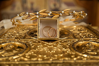 Gold wedding rings and tiara on ornate golden surface