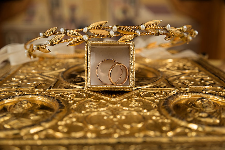Gold wedding rings and tiara on ornate golden surface