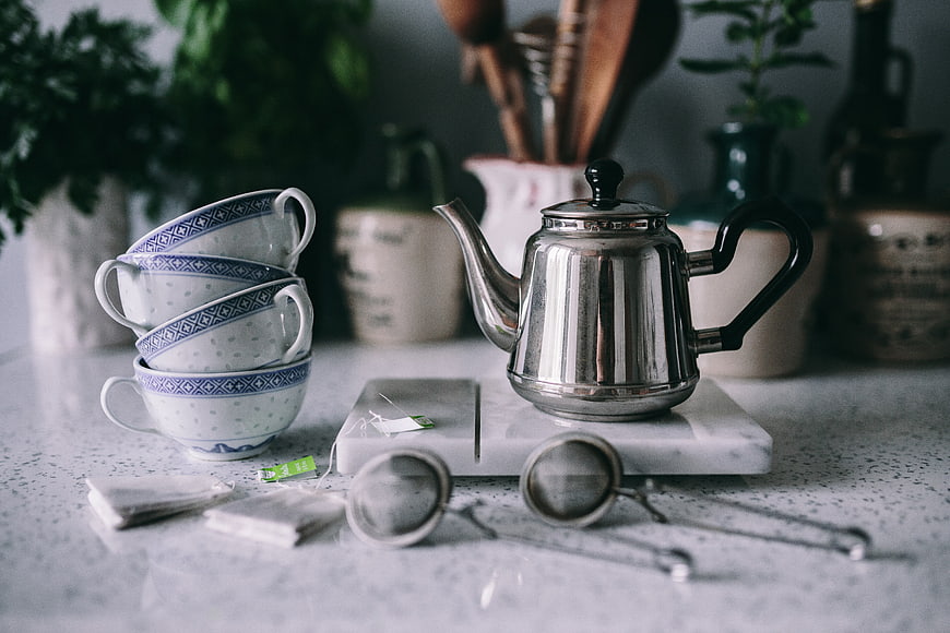 Silver teapot and blue patterned cups on kitchen counter