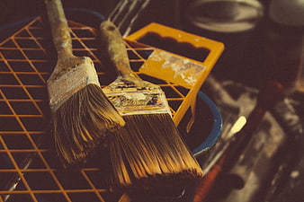 Vintage paint brushes resting on a yellow grid tray