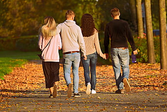 Four friends walking together on an autumn park path