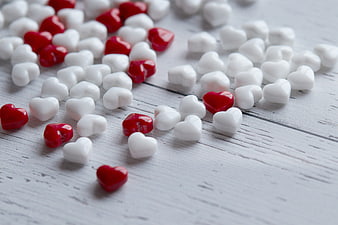 Red and white heart candies on rustic white wood