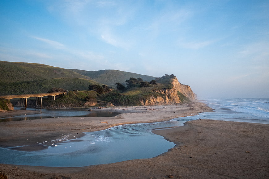 Scenic coastal landscape with bridge, cliffs, and sandy beach