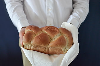 Person holding fresh loaf of bread in white cloth