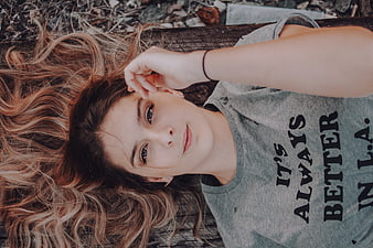 Top-down portrait of a young woman lying on a wooden surface
