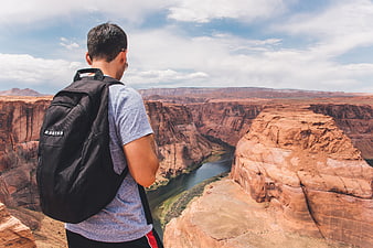 Hiker with backpack overlooking Horseshoe Bend canyon landscape