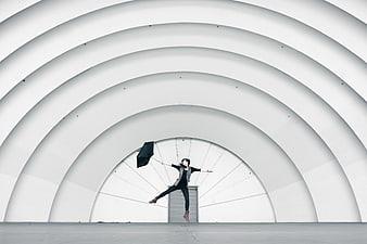 Woman Jumping with Umbrella in White Architectural Tunnel