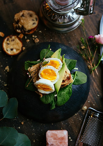 Overhead shot of avocado toast with soft-boiled eggs on dark slate