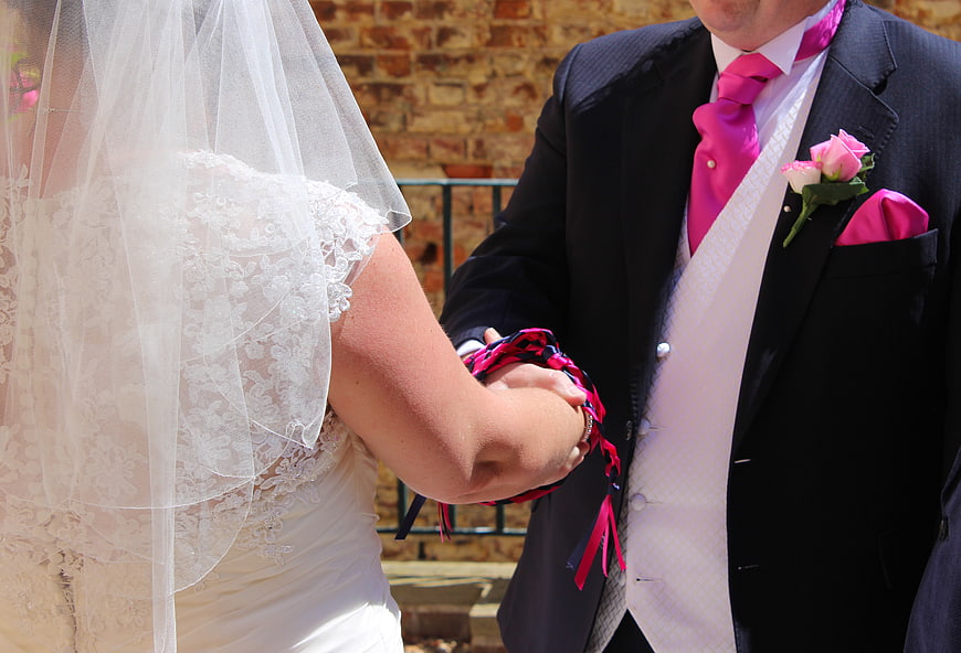 Bride and Groom Tying the Knot with Pink Ribbons