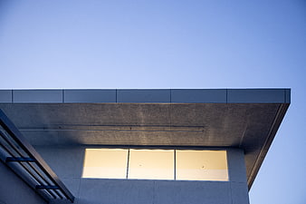 Modern architectural detail with warm window light against blue sky