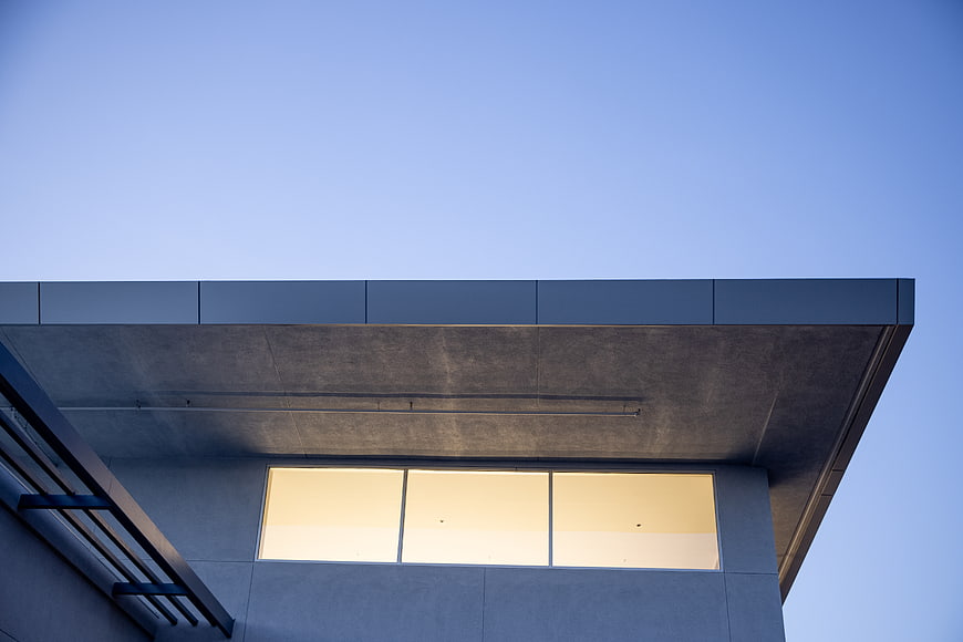 Modern architectural detail with warm window light against blue sky