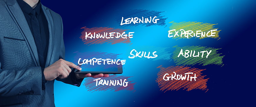 Businessman Holding Tablet With Skill Development Keywords On Blue Background