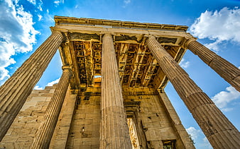 Low angle view of ancient Greek temple columns against blue sky
