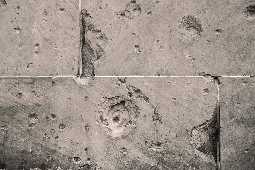 Close-up of weathered concrete wall with holes and cracks