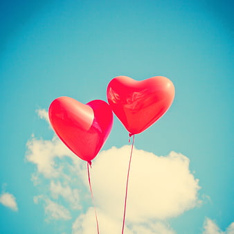 Red Heart Balloons Against Blue Sky