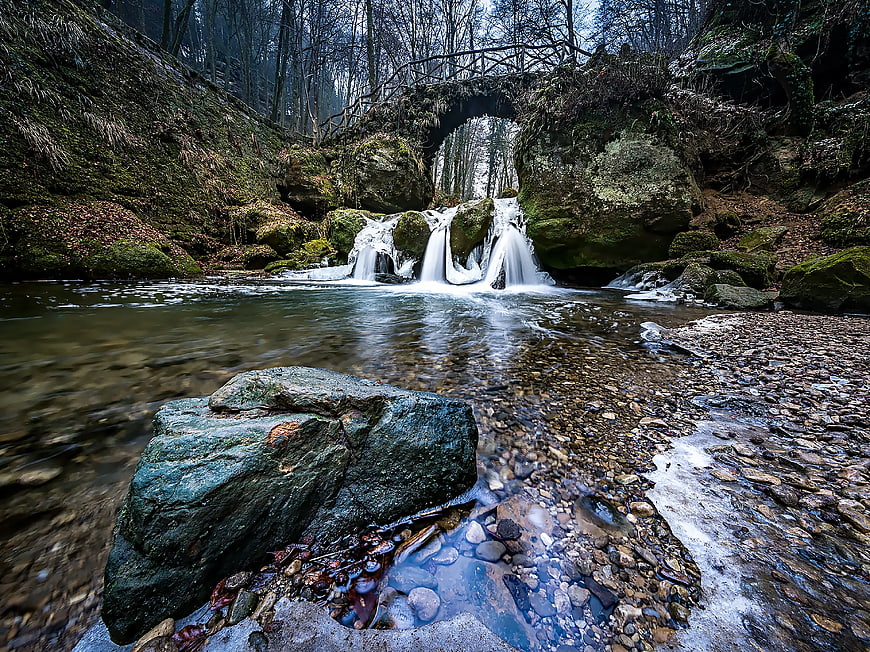 Mossy waterfall in a forest stream with large rocks