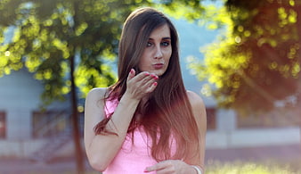Young woman blowing a kiss outdoors in pink top