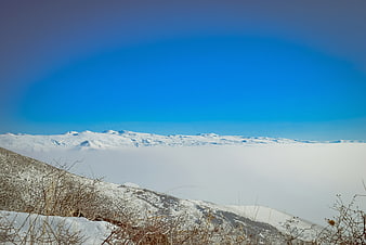 Snowy mountain peaks above sea of clouds