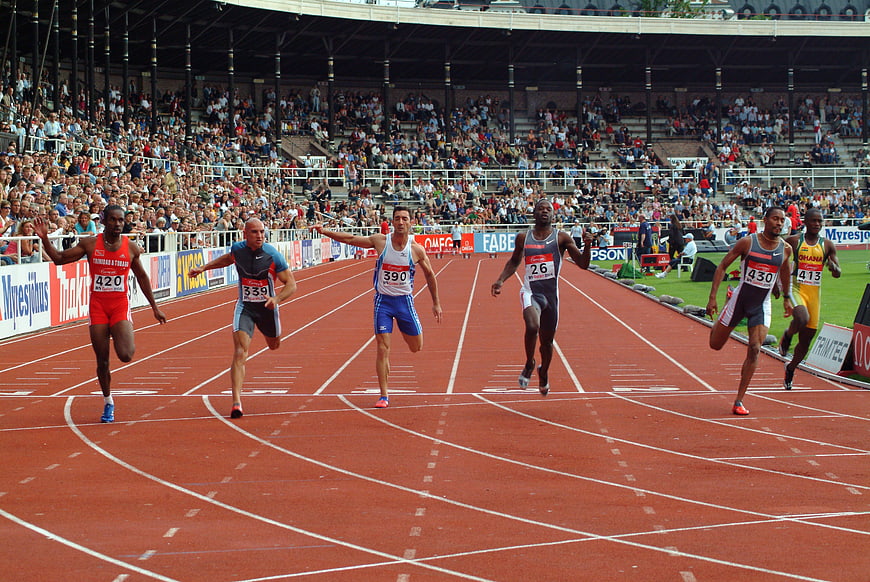 Athletes Sprinting Across Finish Line At Stadium Track