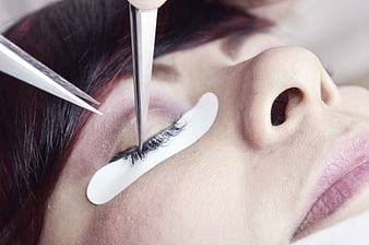 Close-up of eyelash extension application with tweezers