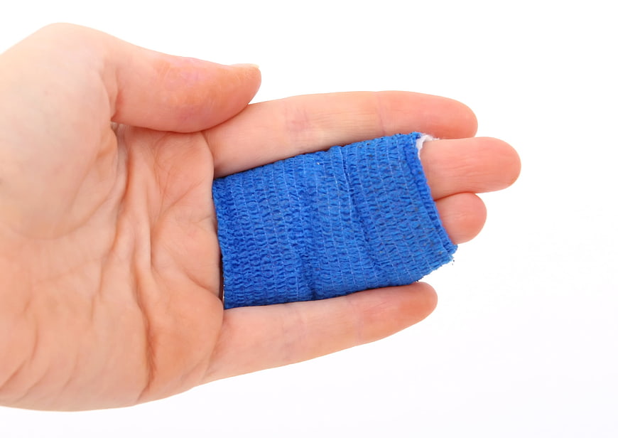 Hand with blue bandage on finger isolated on white background