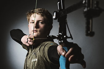 Young Archer Aiming Compound Bow in Dramatic Studio Lighting