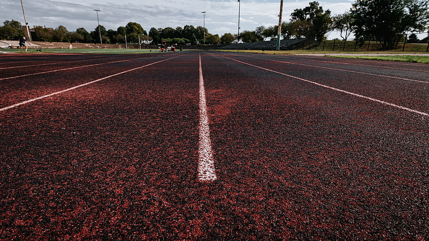Low angle view of red running track with white lane lines