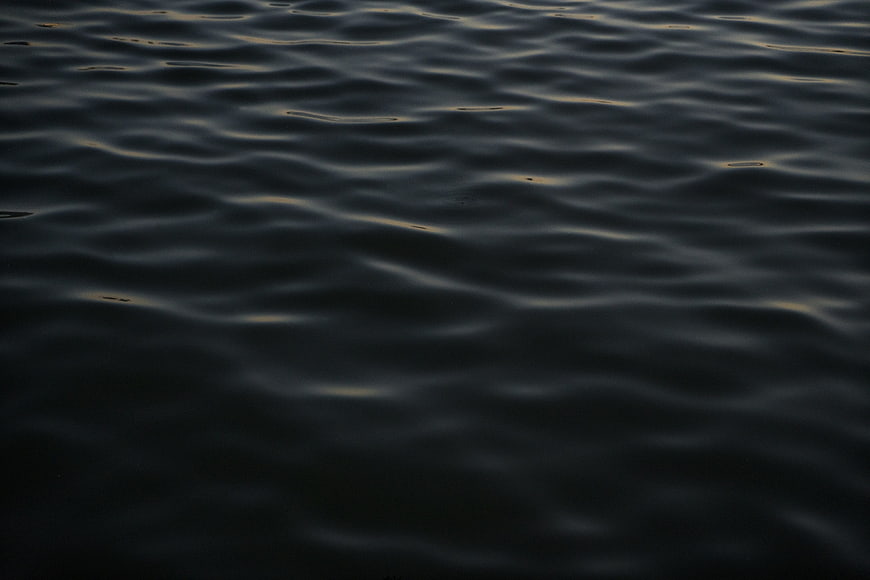 Dark rippling water surface with subtle golden reflections