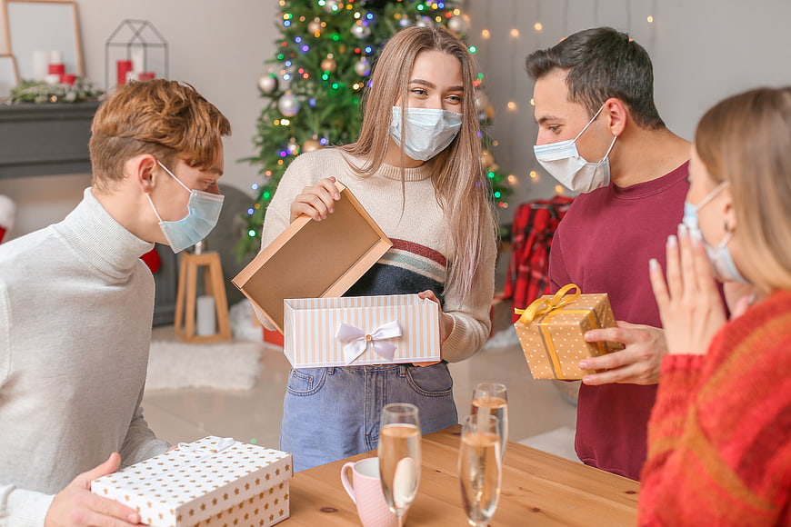 Friends exchanging Christmas gifts wearing face masks