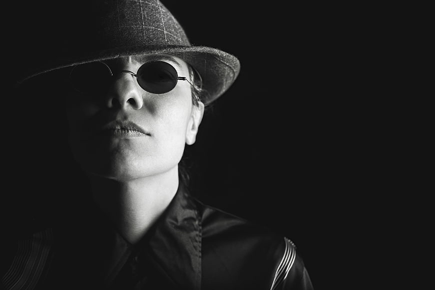 Mysterious woman in fedora and sunglasses black and white portrait