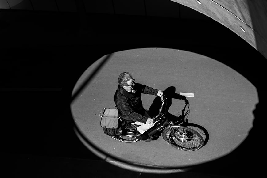 High angle black and white photo of cyclist in spotlight