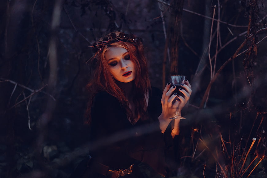 Mysterious woman with goblet in dark forest