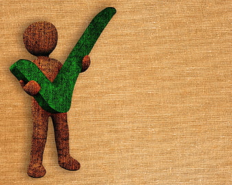 Wooden figure holding green check mark on textured background
