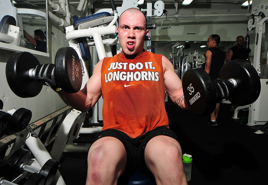 Man lifting dumbbells in gym with intense expression