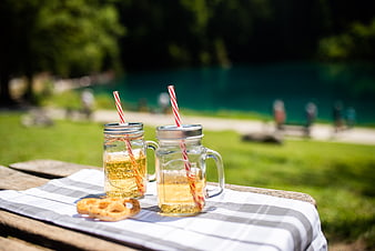 Refreshing lemonade in mason jars with pretzels on a picnic table by a lake