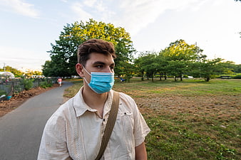 Young man wearing blue face mask walking in park