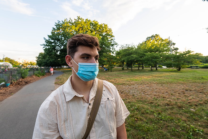 Young man wearing blue face mask walking in park