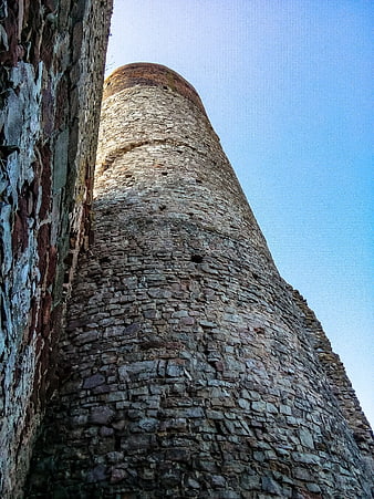 Low angle view of ancient stone castle tower against blue sky