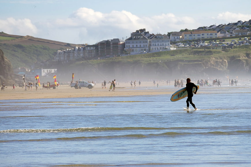 Surfer Walking Into Ocean At Busy Beach