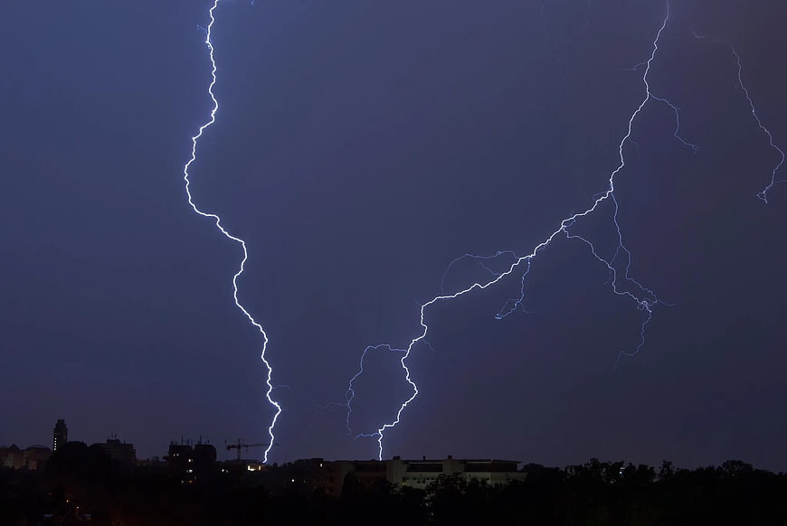 Dramatic Lightning Bolts Striking Over City Skyline at Night