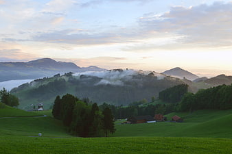 Misty Morning Landscape of Green Rolling Hills and Mountains