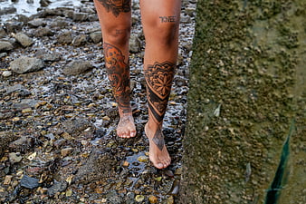 Tattooed Woman Legs Walking on Rocky Beach Shore